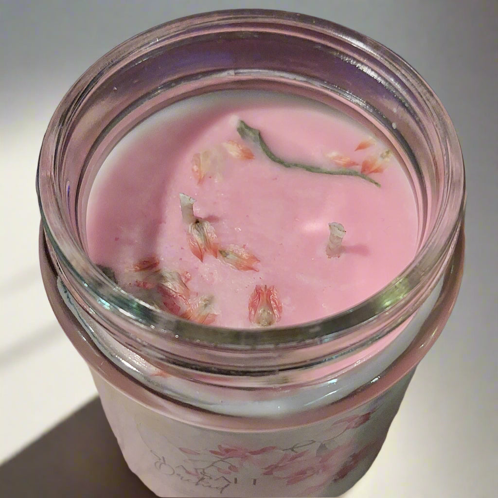 Pink glass container with floral design on a pink surface