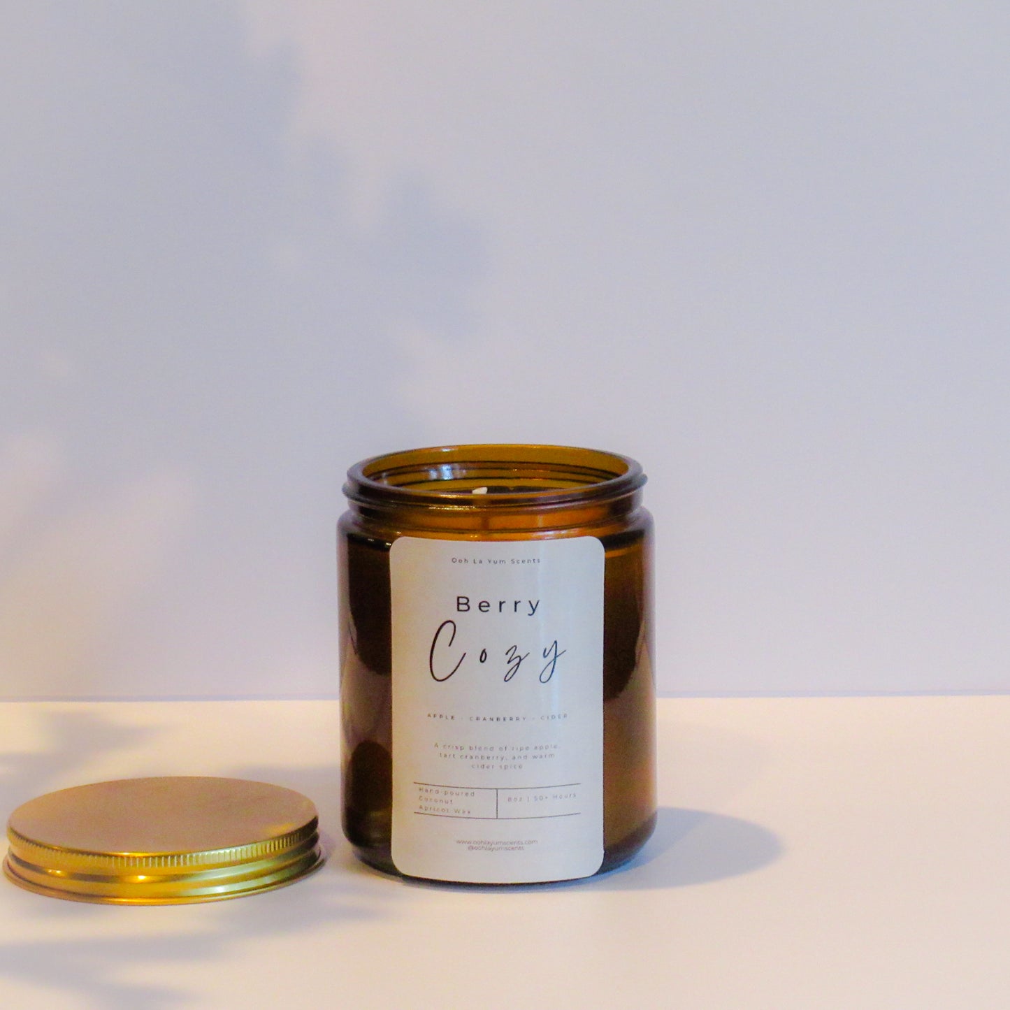 Candle jar with a label on a light background with label 'Berry Cozy"