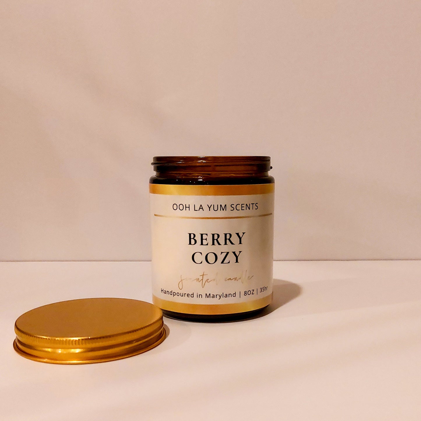 Candle jar labeled 'Berry Cozy' by Ooh La Yum Scents on a light background