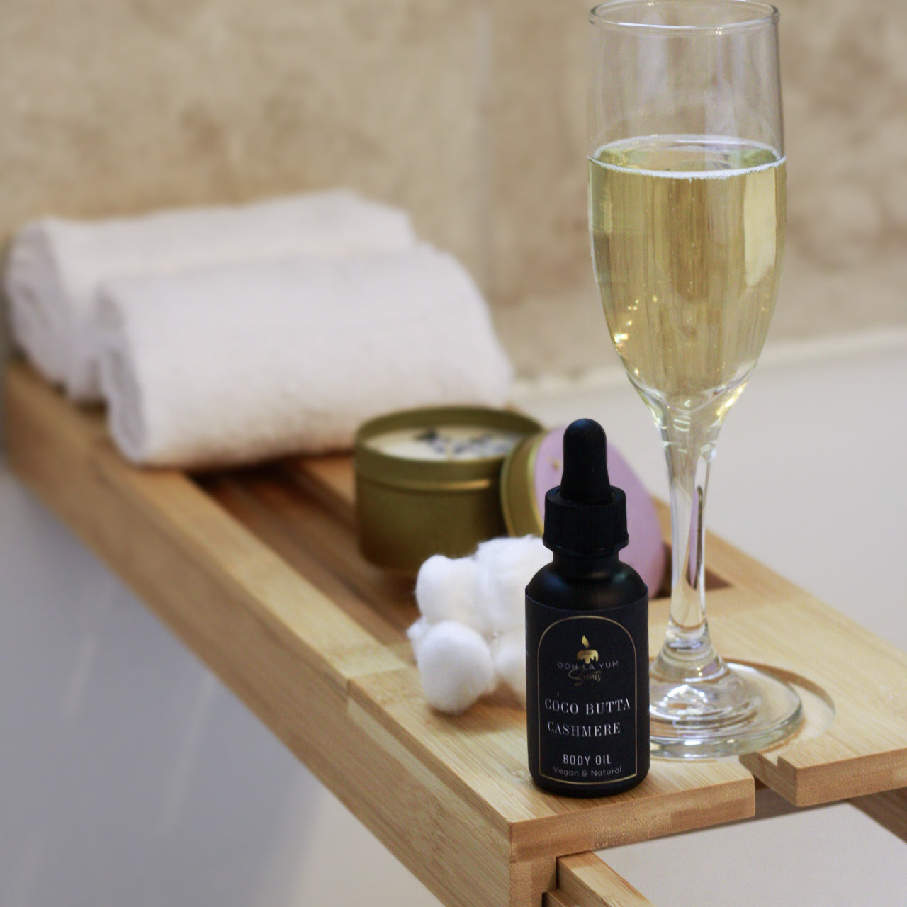 Bottle of CoCo Bette Creme, glass of champagne, and bath items on a wooden tray.