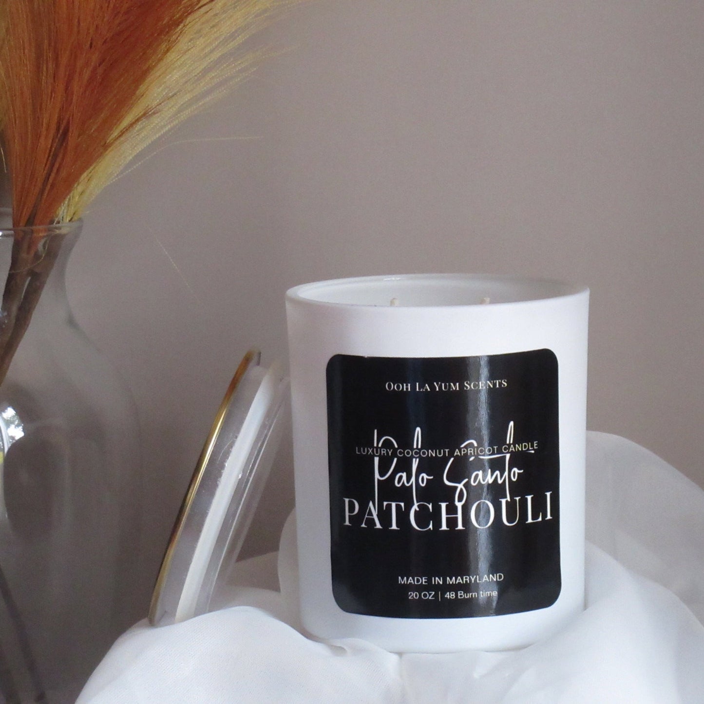 Candle with 'Palo Santo Patchouli' label on a white surface with a blurred background