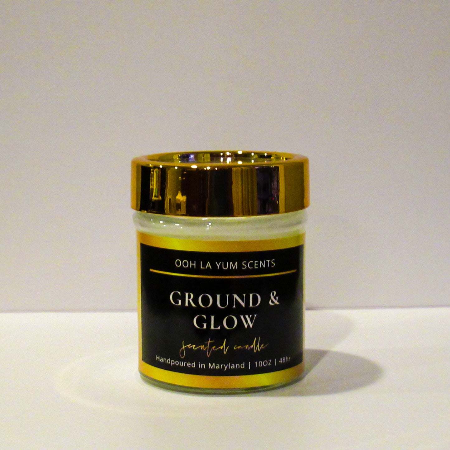 Candle jar labeled 'Ground & Glow' by Ooh La Yum Scents on a white background