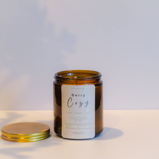 Candle jar with a label on a light background with label 'Berry Cozy"