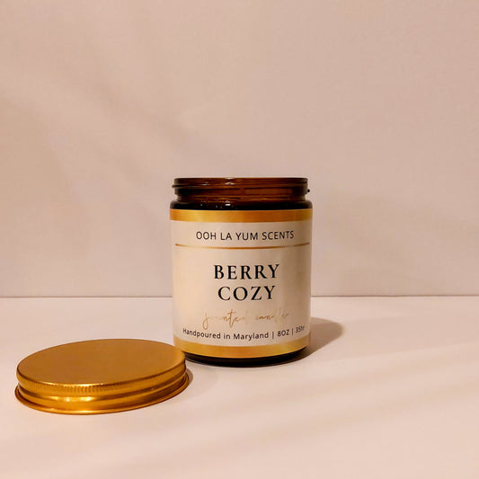 Candle jar labeled 'Berry Cozy' by Ooh La Yum Scents on a light background
