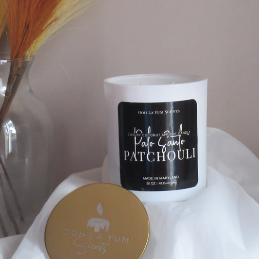 White candle with black label on a white surface, with a blurred background