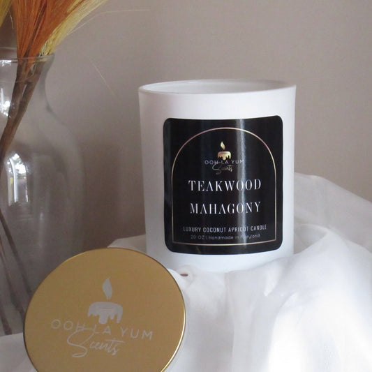 Candle with 'Teakwood Mahogany' label and 'Oo La Yum Scents' logo on a white surface.