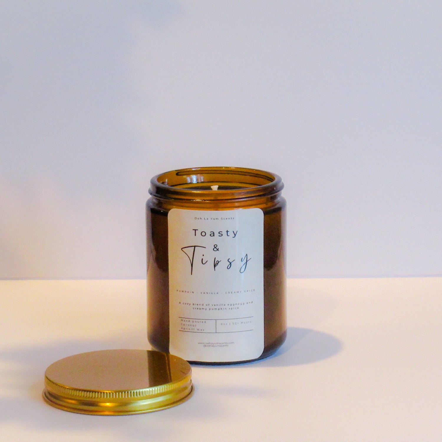 Candle jar with a label reading 'Toasty & Tipsy' on a light background