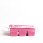 Pink wax melts in a clear plastic container on a white background