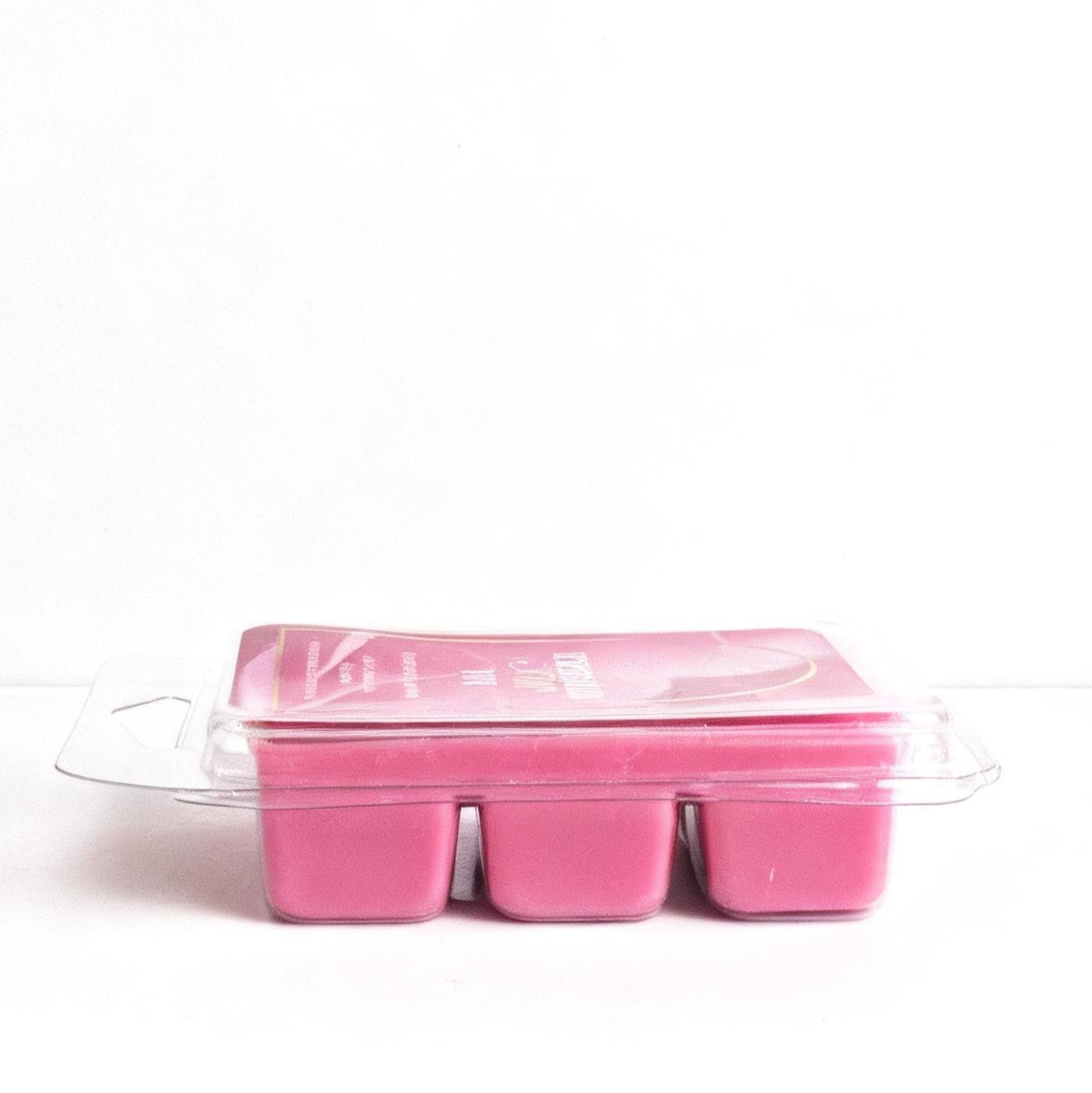 Pink wax melts in a clear plastic container on a white background